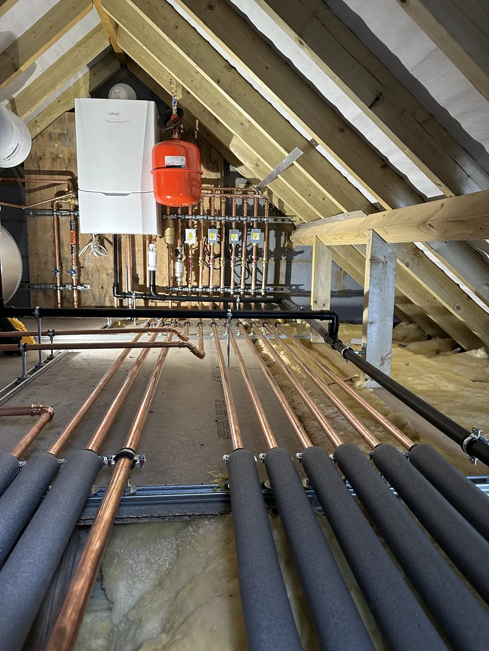 Loft boiler installation with insulated copper pipework across floor joists — plumbing Basingstoke