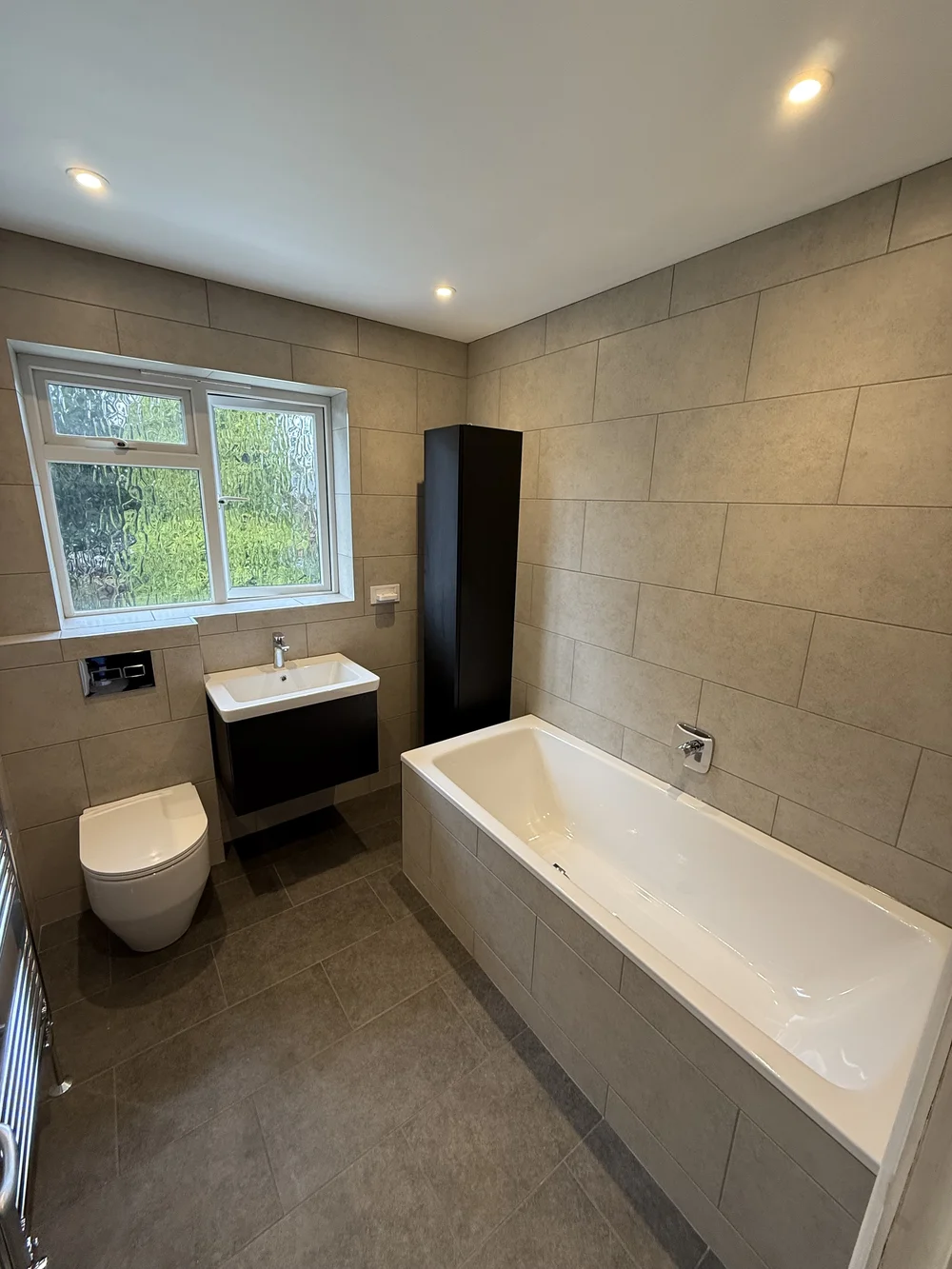 Fitted family bathroom with black vanity, tall storage and built-in bath — bathroom installers Basingstoke