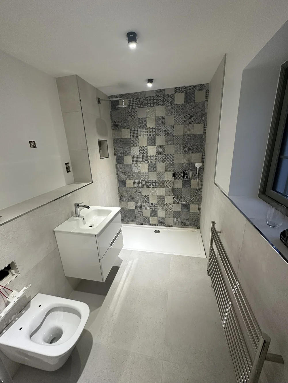 Modern shower room with patchwork feature tiles, white vanity and heated ladder rail — bathroom renovation Basingstoke