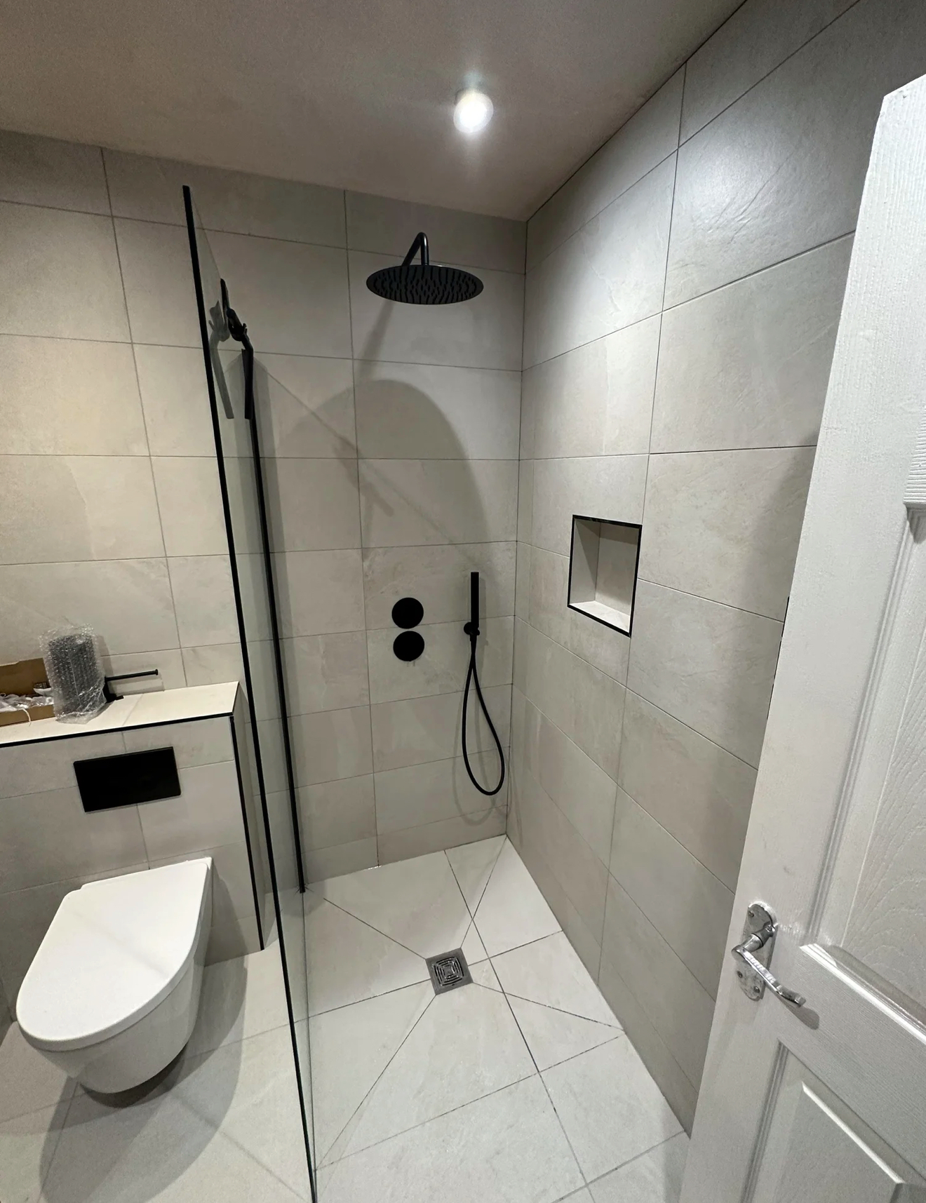 Matte black walk-in shower with rainfall head and recessed niche — wet room Basingstoke