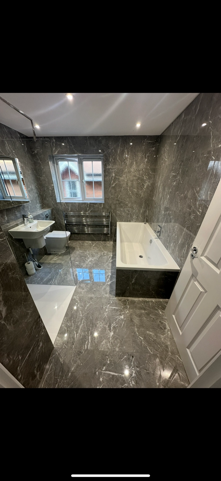 Grey marble family bathroom with double-ended bath and chrome towel rail — Basingstoke