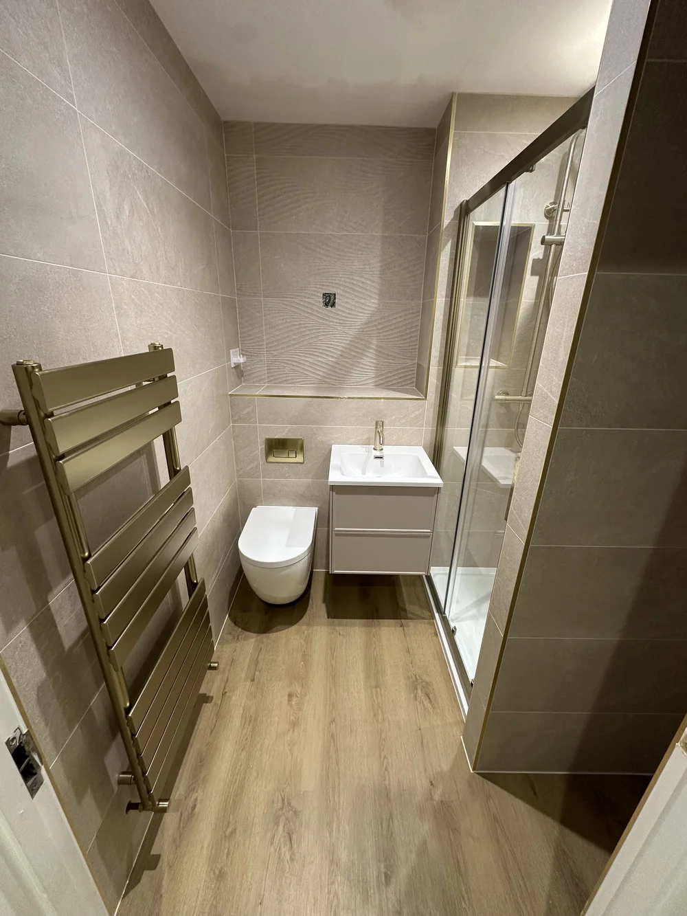 Modern shower room with brushed brass trim, sliding glass door and designer radiator — Basingstoke bathroom fitters