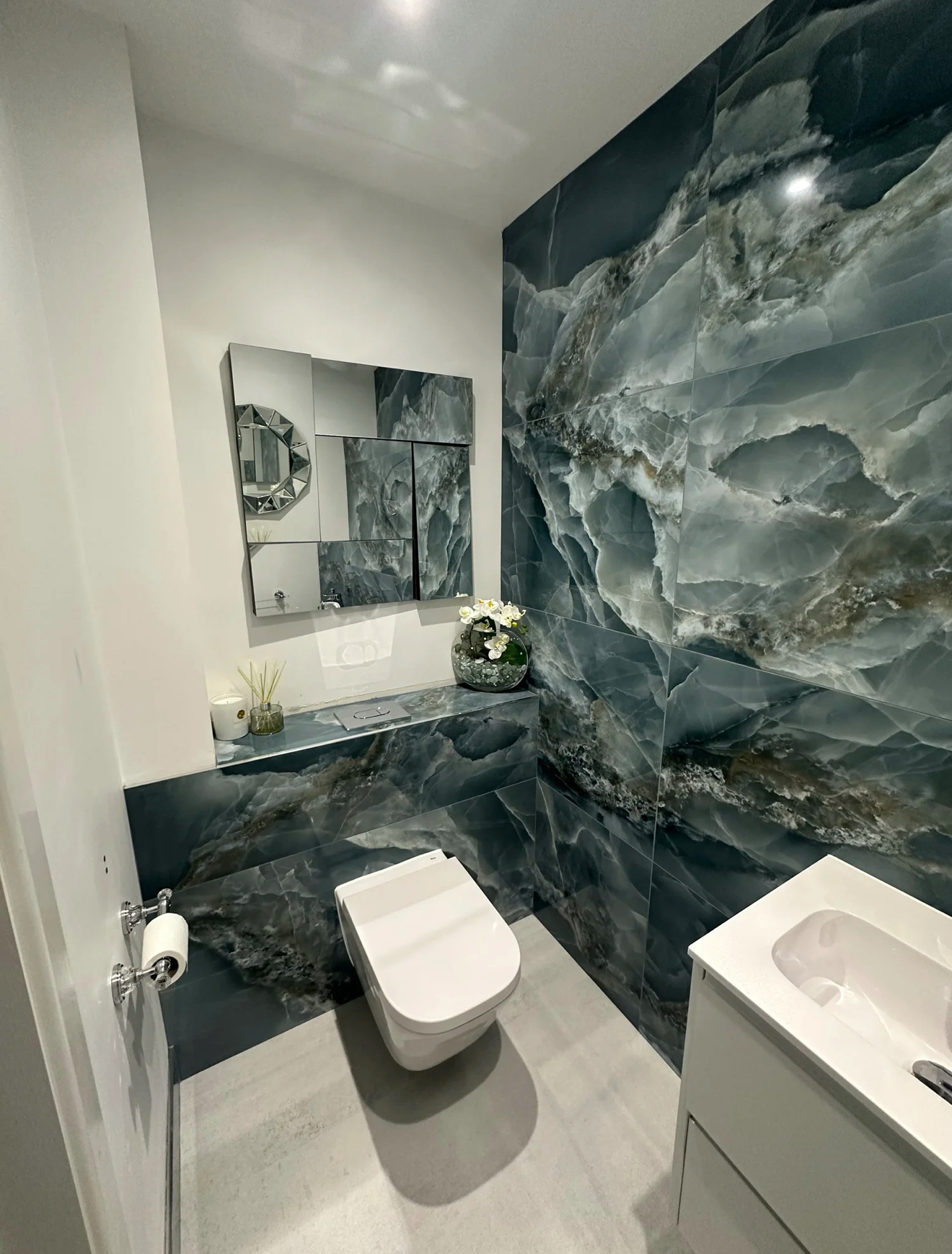 Green marble cloakroom with wall-hung WC and mirrored cabinet — bathroom refurbishment Basingstoke