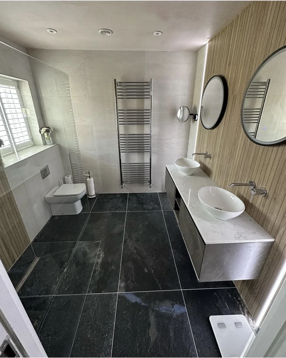 Slate-floored master bathroom with oak fluted feature wall, twin vessel basins and quartz vanity — bathroom design Basingstoke
