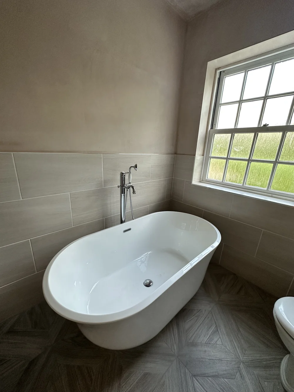 Traditional freestanding double-ended bath with chrome floor-mounted mixer and parquet floor — bathroom installation Basingstoke