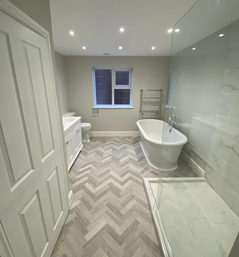 Traditional family bathroom with freestanding roll-top bath, herringbone floor and marble walk-in shower — bathroom installation Basingstoke