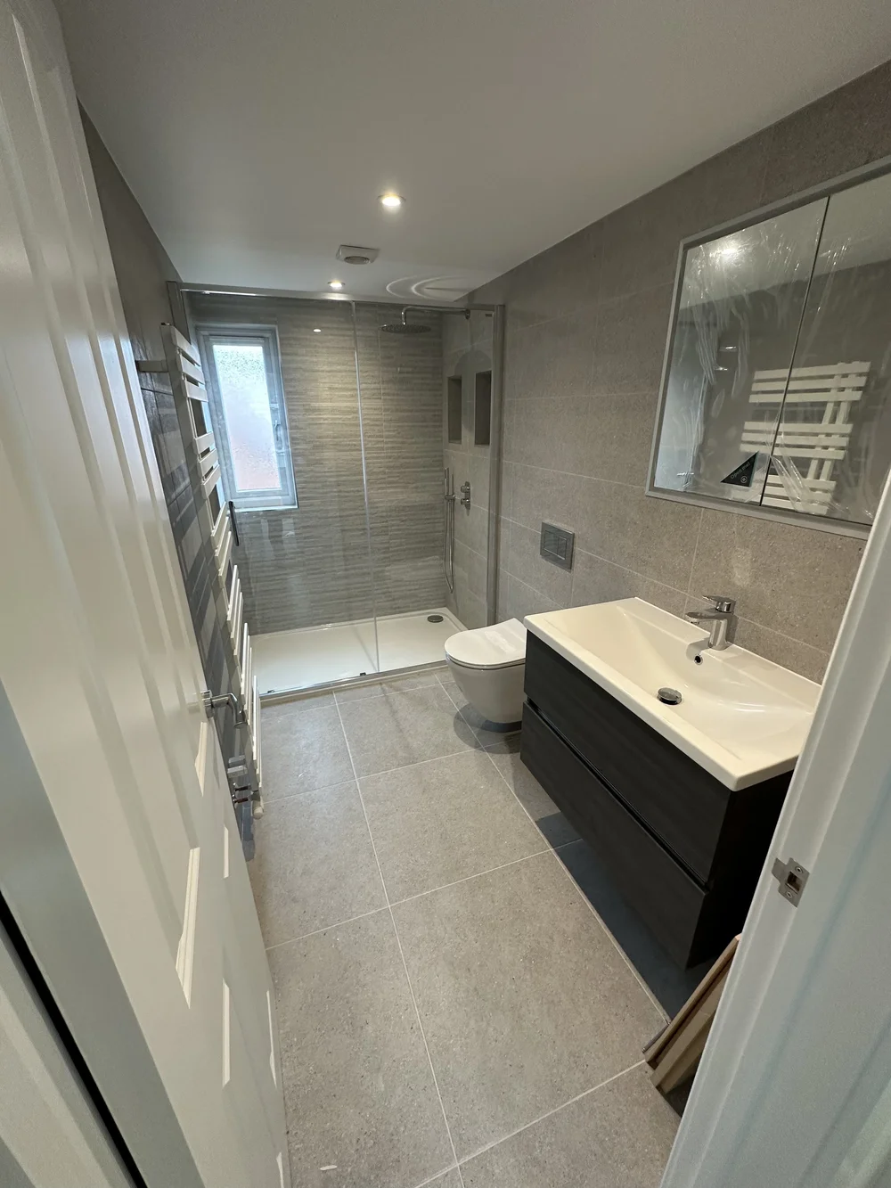 Grey stone-tiled shower room with graphite vanity and glass shower enclosure — bathroom installation Basingstoke