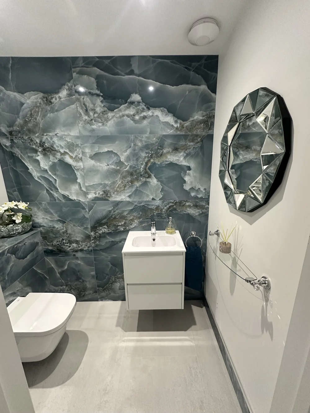 Luxury cloakroom with blue onyx feature wall, wall-hung WC and jewel-cut mirror — bathroom installation Basingstoke