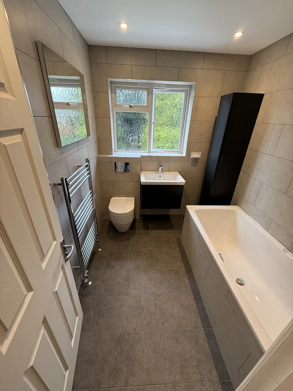 Compact family bathroom with black vanity, wall-hung WC and built-in bath — bathroom installation Basingstoke