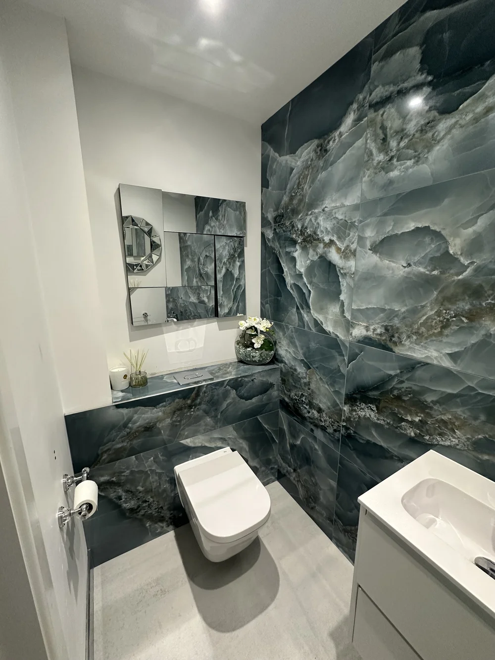 Bespoke cloakroom with full-height blue onyx feature wall and faceted mirror — bathroom design Basingstoke