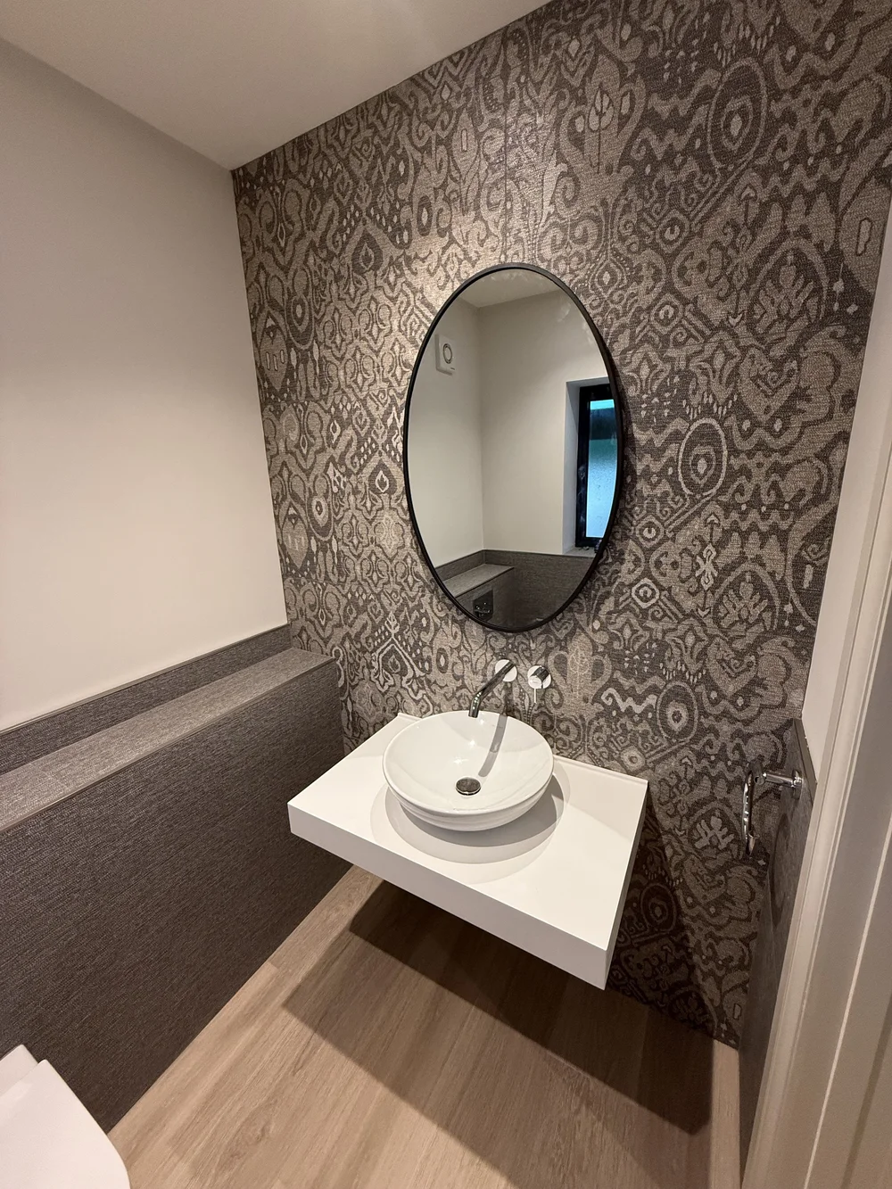 Feature-wall cloakroom with round black mirror and vessel basin — bathroom design Basingstoke