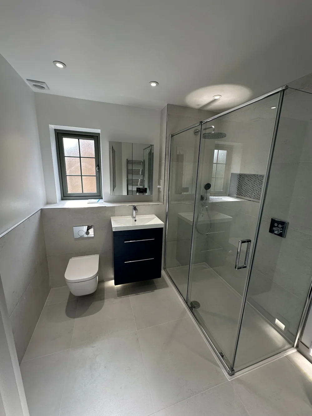 Fitted shower room with navy vanity, wall-hung WC and large glass shower enclosure — bathroom installation Basingstoke