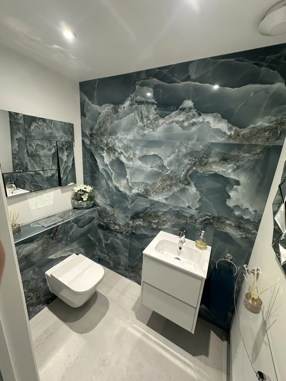Cloakroom with blue onyx feature wall, wall-hung WC and floating white vanity — bathroom design Basingstoke