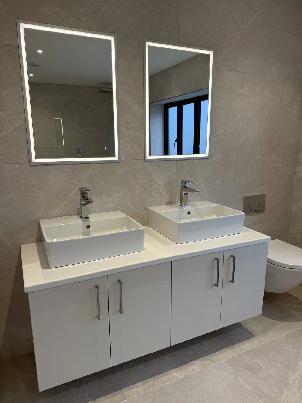 Twin countertop basins with LED mirrors on wall-hung vanity — ensuite installation Basingstoke