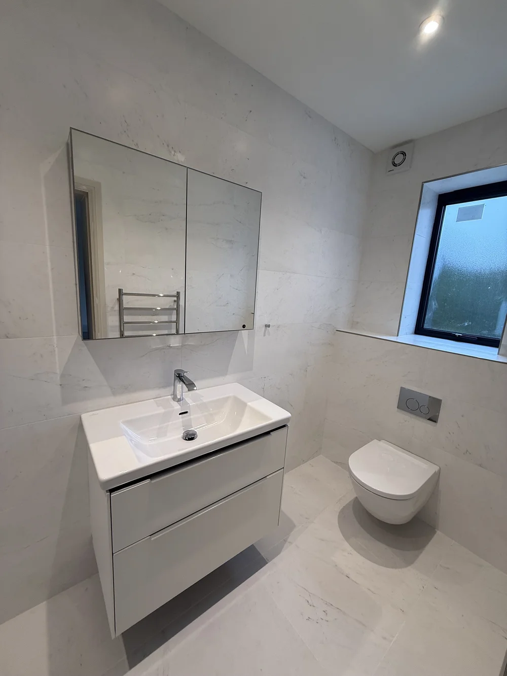 White marble family bathroom with wall-hung vanity and concealed cistern — Basingstoke