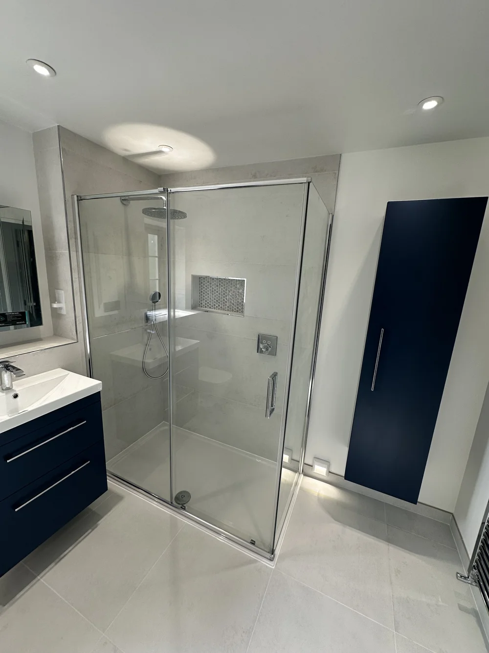 Contemporary shower room with navy wall cabinet, floating vanity and walk-in shower — bathroom installation Basingstoke