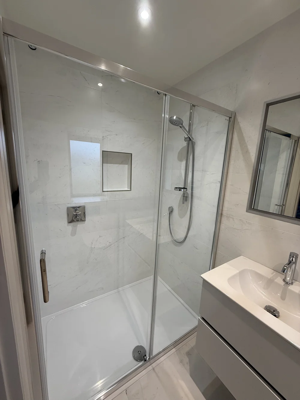 Marble shower enclosure with sliding door and recessed niche — bathroom renovation Basingstoke