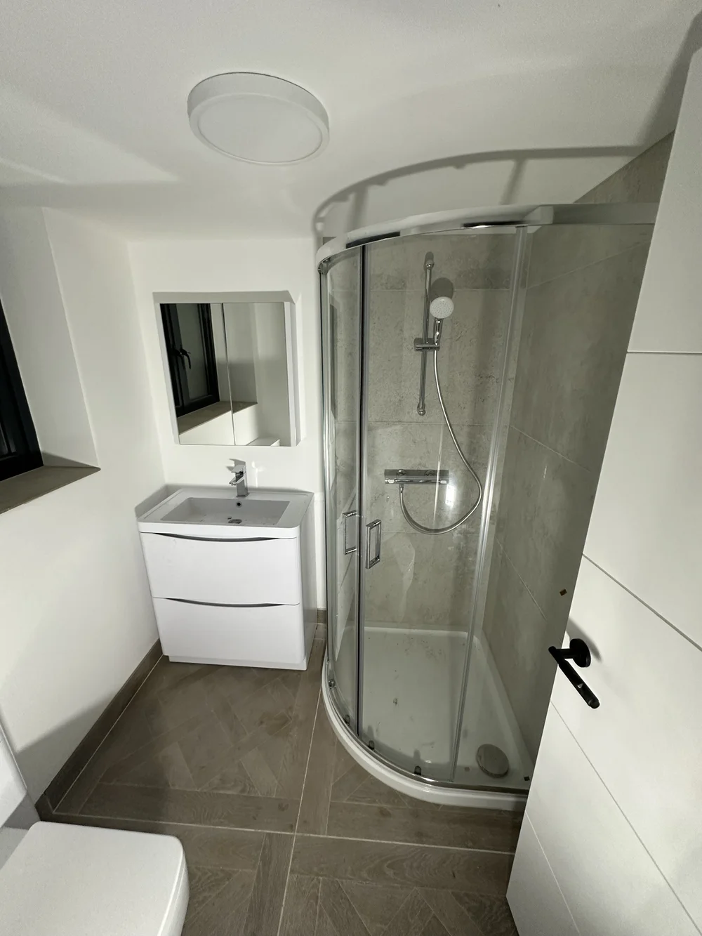 Loft shower room with quadrant enclosure, herringbone tile floor and floor-standing vanity — bathroom installation Basingstoke