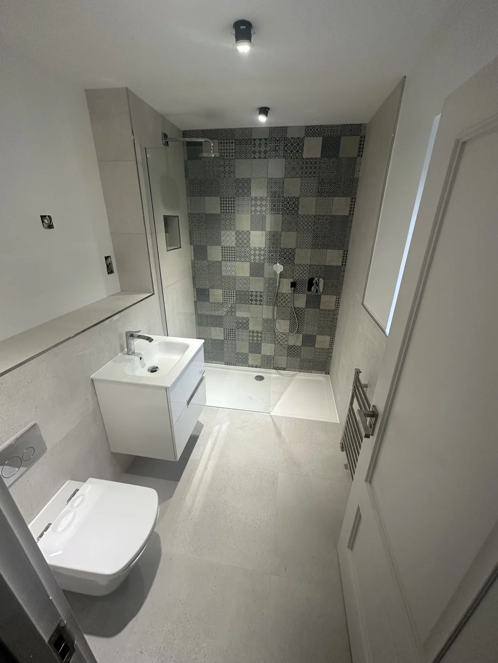 Compact shower room with patchwork feature wall and floating white vanity — bathroom installation Basingstoke