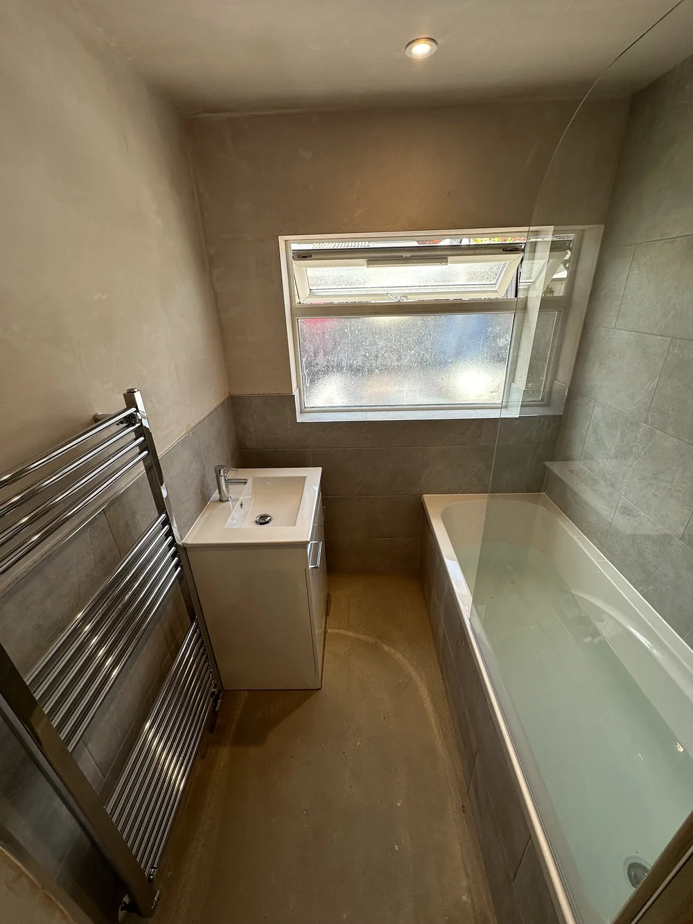 Compact family bathroom mid-renovation with fresh plaster, stone tiling and new bath — bathroom renovation Basingstoke