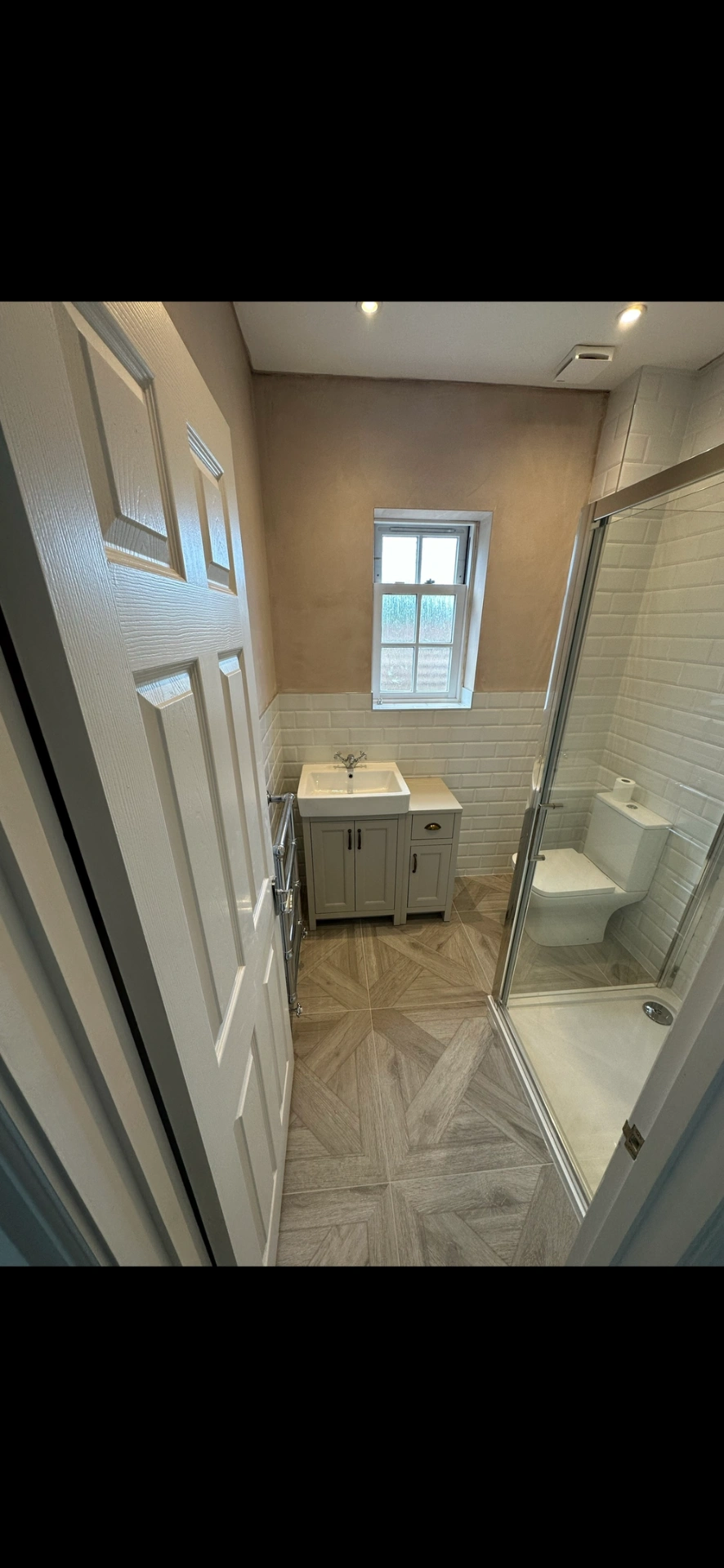Compact shower room with shaker vanity, beveled metro tiles and chevron parquet floor — bathroom installation Basingstoke