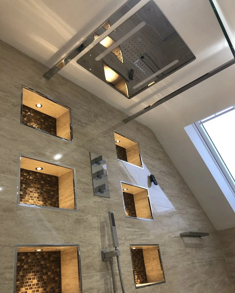 Ceiling rainfall panel with LED strip lighting over travertine walk-in shower — luxury bathroom installation Basingstoke