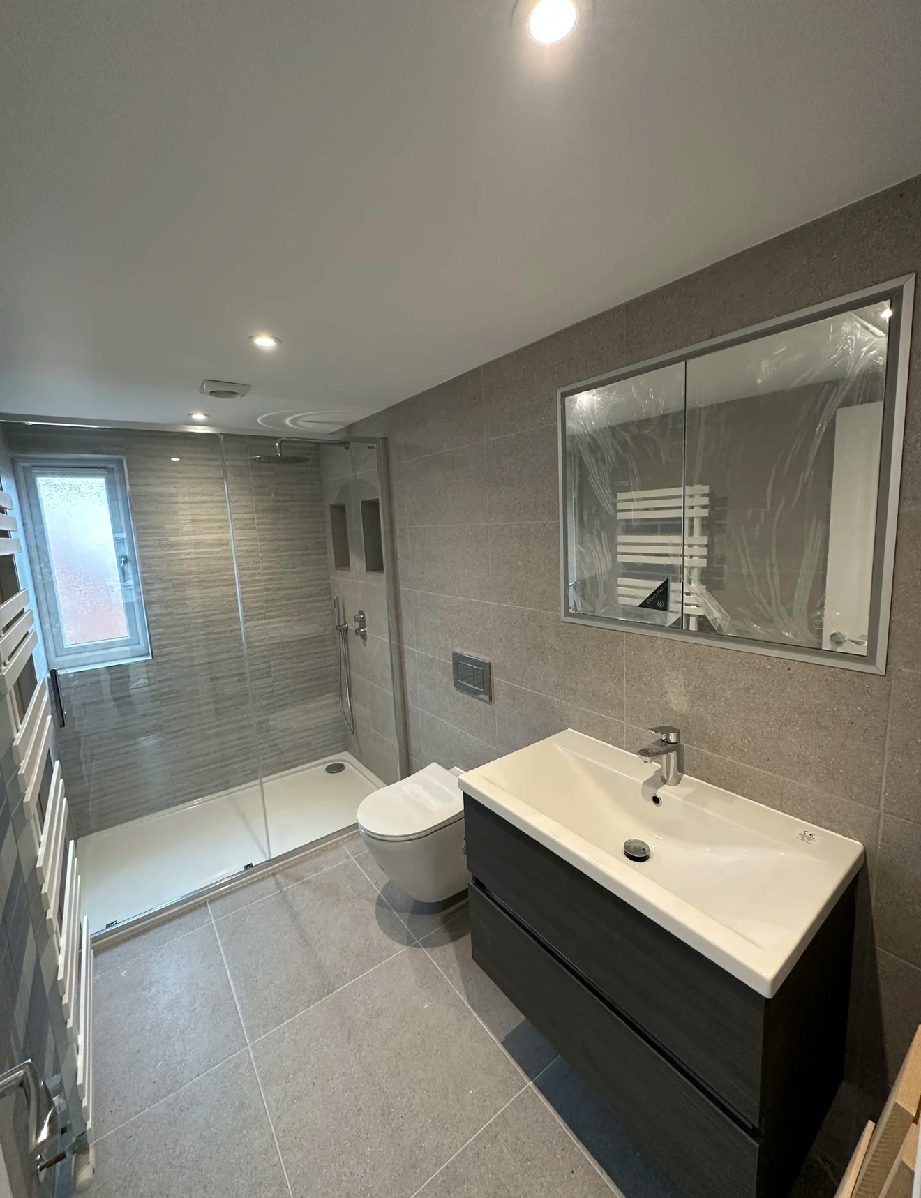 Grey stone-tiled shower room with floating vanity and wall-hung WC — bathroom installation Basingstoke